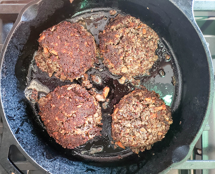 4 veggie burgers cooking in a skillet