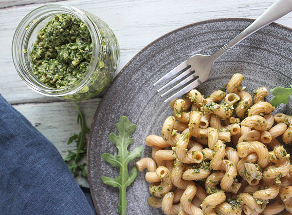 arugula pesto on a plate with a jar of pesto sauce on the side