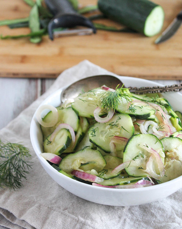 cucumbers and onions sliced thin in a white bowl