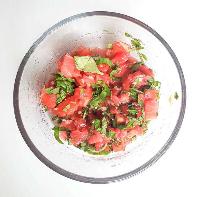 an overhead view of tomatoes and basil mixture in a bowl