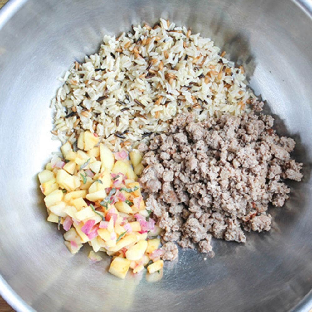 the ingredients of stuffed squash in a bowl, apples, sausage and rice