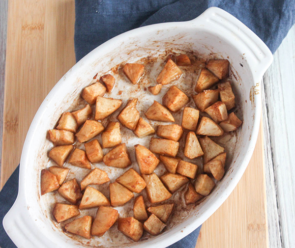 Overhead view of baking dish with diced apples with cinnamon, maple syrup and butter