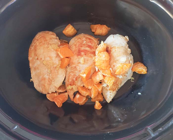 chicken in a slow cooker with orange slices on top