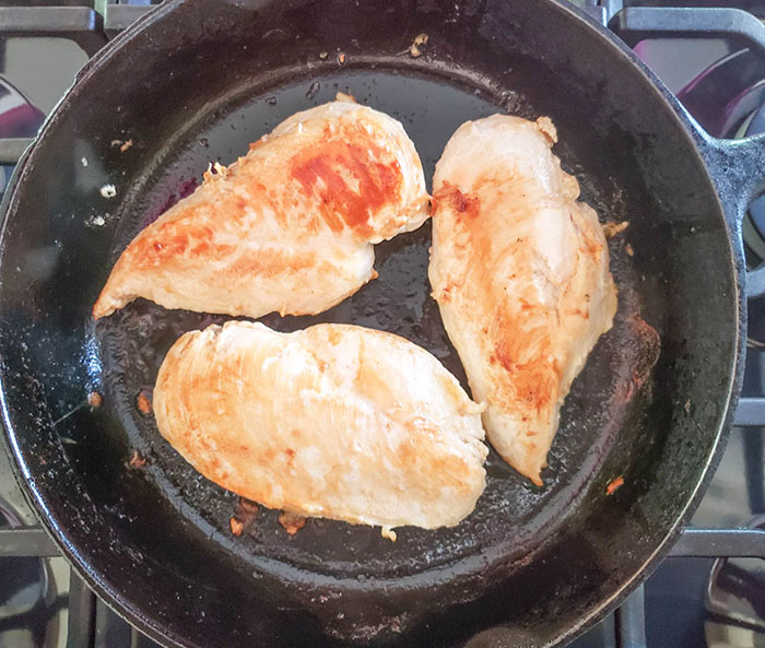 Chicken breasts cooking in a skillet