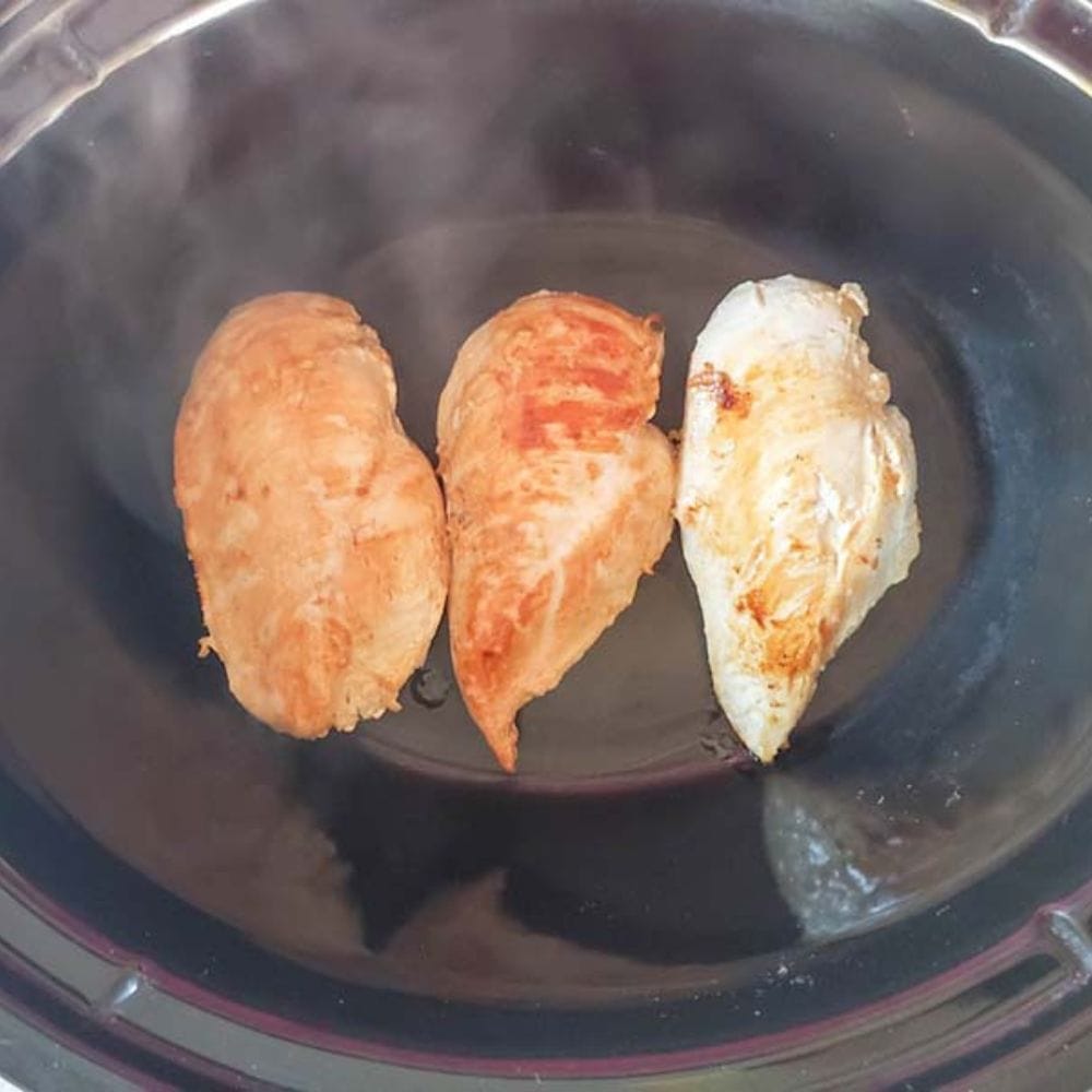 golden brown boneless chicken breasts in a slow cooker