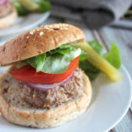 jerk chicken burger on a roll with lettuce and tomato