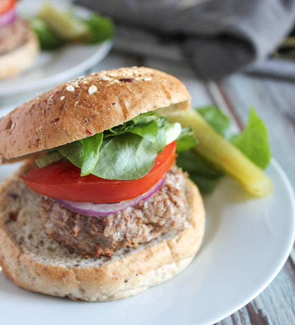 jerk chicken burger on a roll with lettuce and tomato