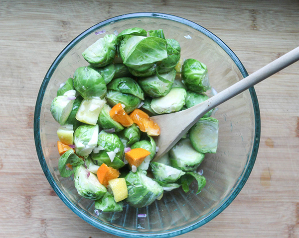 brussels sprouts and citrus in a mixing bowl with a spoon