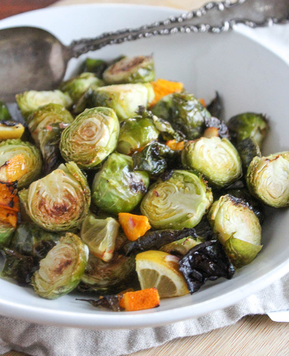 Roasted Brussels Sprouts in a white bowl with a serving spoon