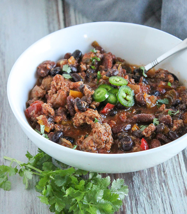 a bowl of turkey chili with a spoon in it with jalapeno slices on top