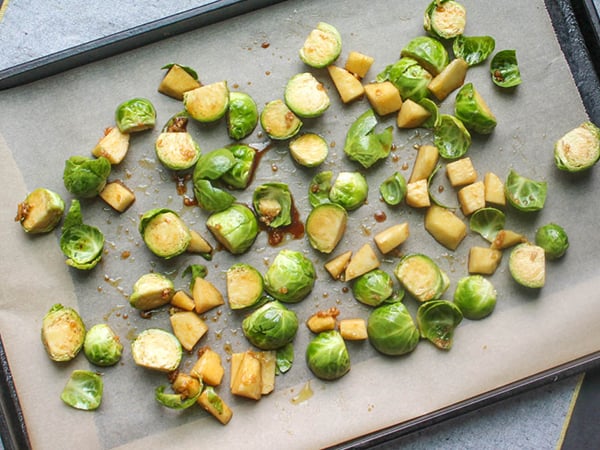 a picture of brussels sprouts and apples on a sheet pan