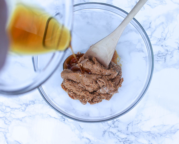 syrup pouring into a bowl with peanut butter mixture