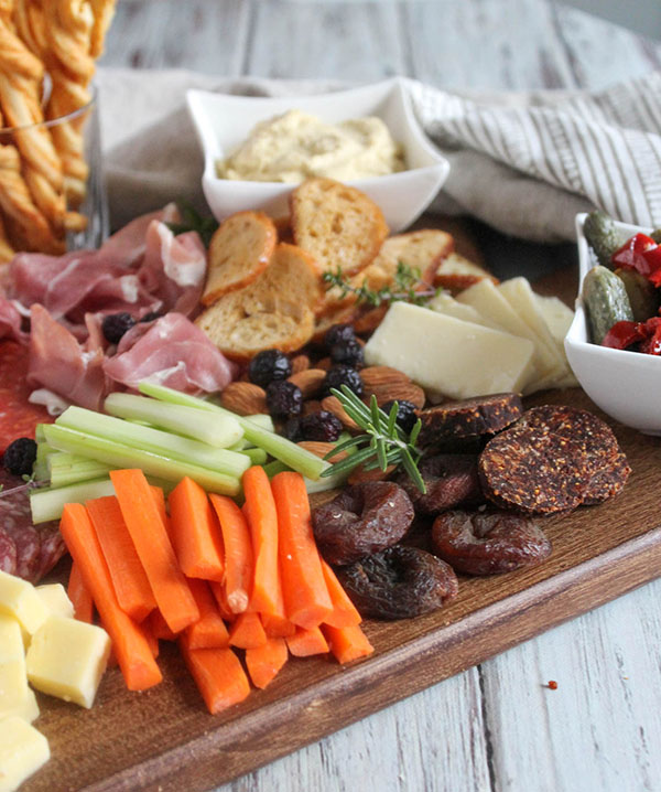 carrots, celery, dried apricots and fig salami on a board