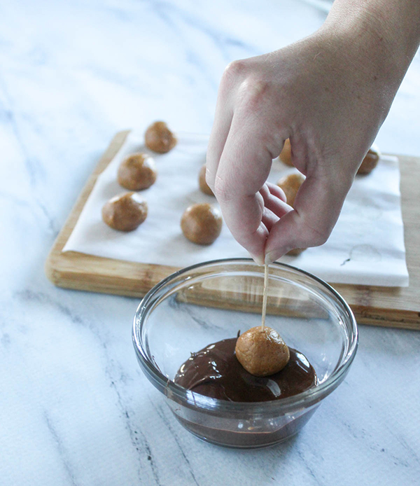 dipping the peanut butter balls into the melted chocolate