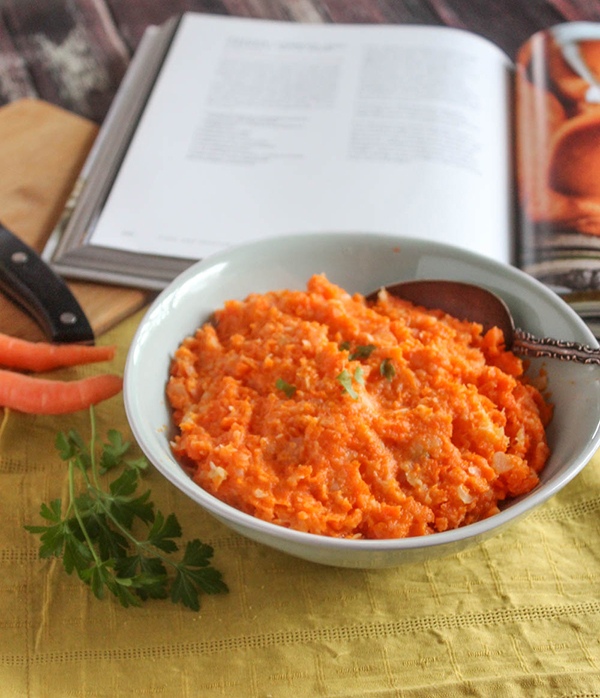 carrot and turnip mash in a bowl with the cookbook behind it