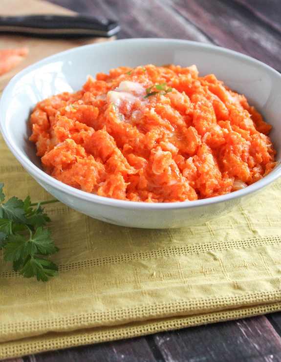 A close up view of turnip and carrot mash in a bowl with melted butter on top