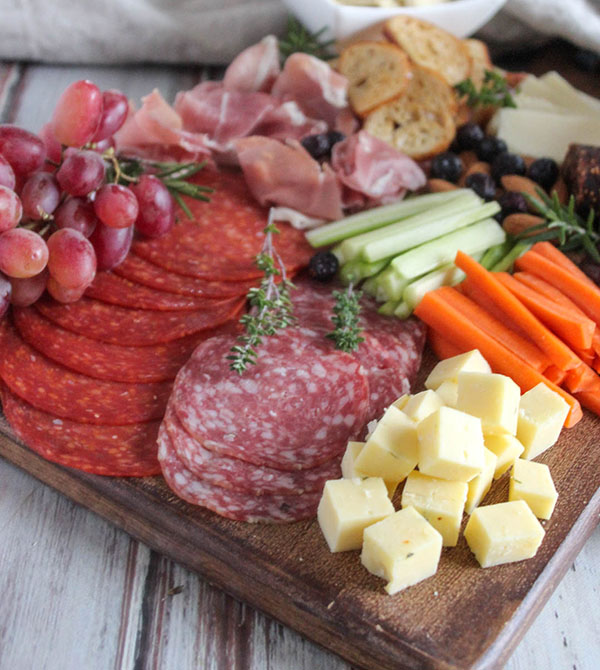 a close up view of cheese cubes salami and pepperoni on a cheese board