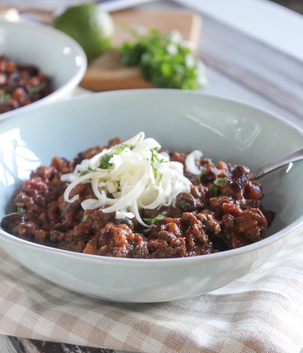 a close up photo of easy chili in a bowl topped with cheese