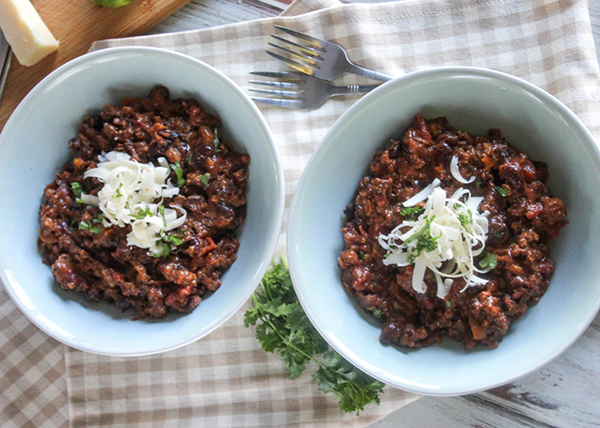 an overhead view of two bowls of chili with shredded cheese