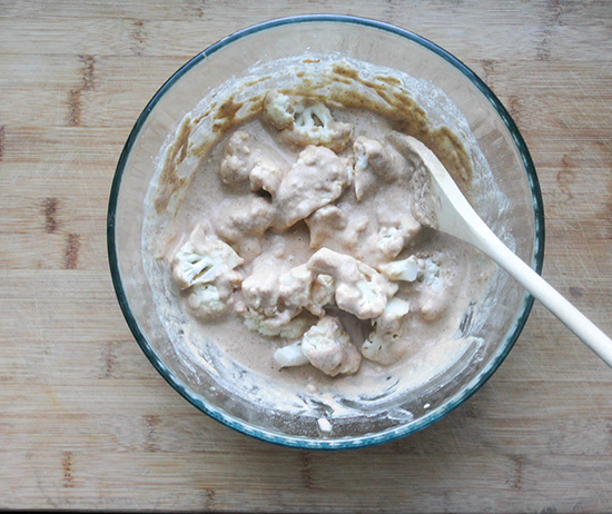 a picture of cauliflower florets in a bowl with batter