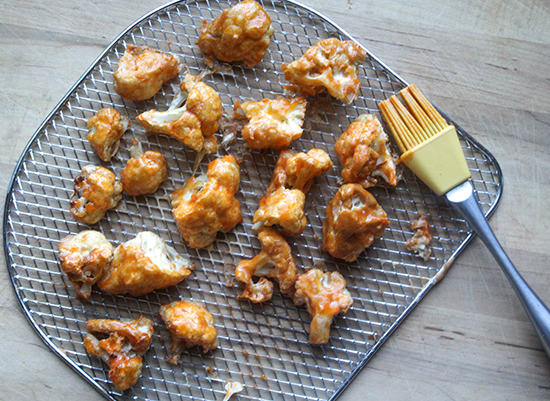 cauliflower bites on an air fryer tray with hot sauce