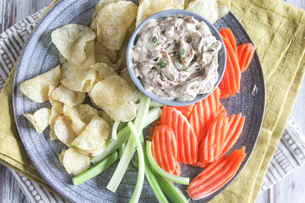 an overhead view of onion dip with chips, carrots and celery sticks