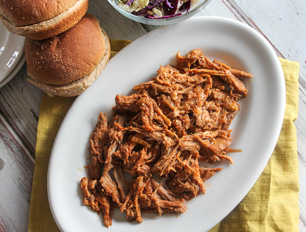 a view looking down at pulled pork with rolls on the side