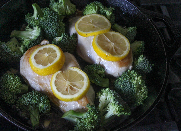 chicken with lemon slices on top with broccoli on the side