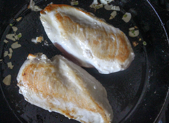 boneless chicken breasts in a skillet heating up