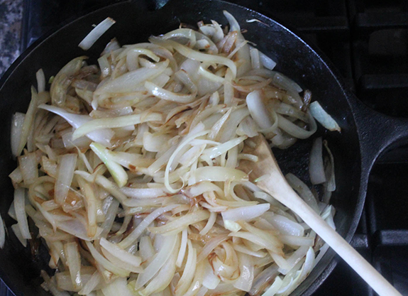 overhead view of onions cooking in a skillet