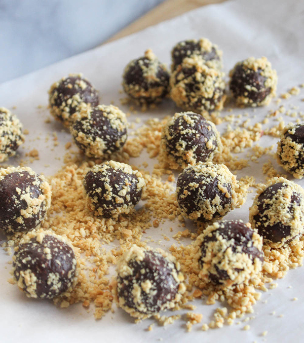 Energy bites rolled in chopped peanuts on parchment paper