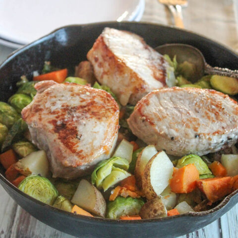 pork chops in a cast iron skillet with vegetables