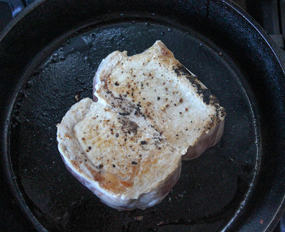 two boneless pork chops in a skillet