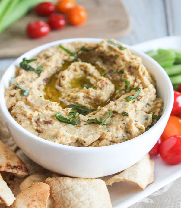 a bowl of hummus with pita chips and tomatoes