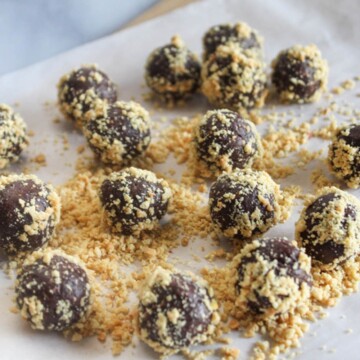 date balls on parchment paper with chopped peanuts