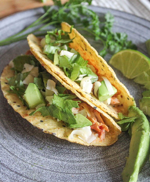 A close up of two taco shells filled with taco meat and lettuce, avocado