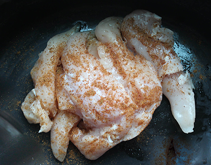 Raw chicken in crockpot with seasoning