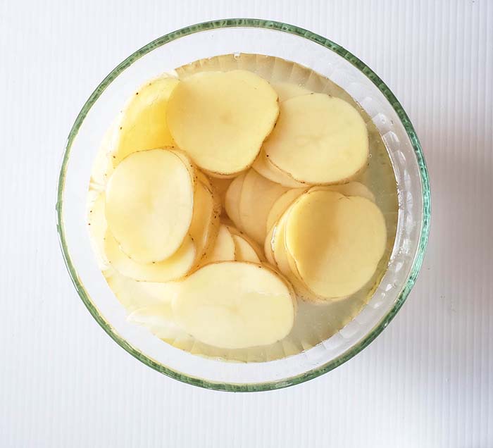 potato slices in a bowl with water