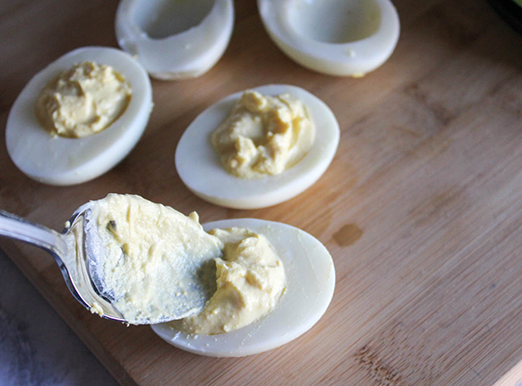 This image is to show step six of recipe. Spoon is filling the egg whites.  Three egg whites are filled and two are remaining to fill.