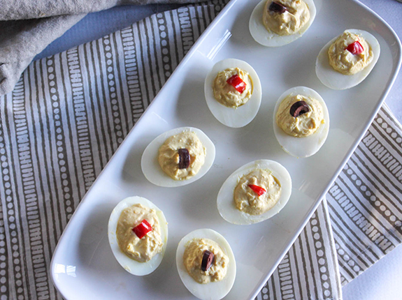 an overhead view of deviled eggs on a white platter