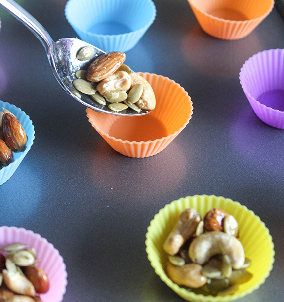 a spoon adding nuts into cupcake liner