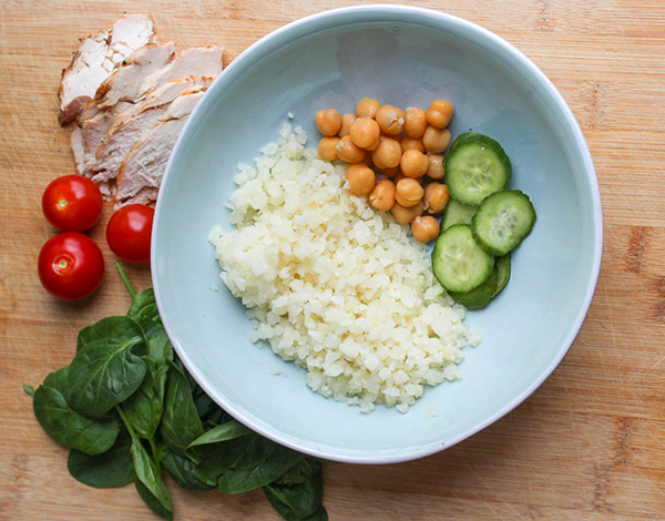 The ingredients chickpeas, cauliflower rice, spinach cucumbers, tomaoes, spinach and chicken