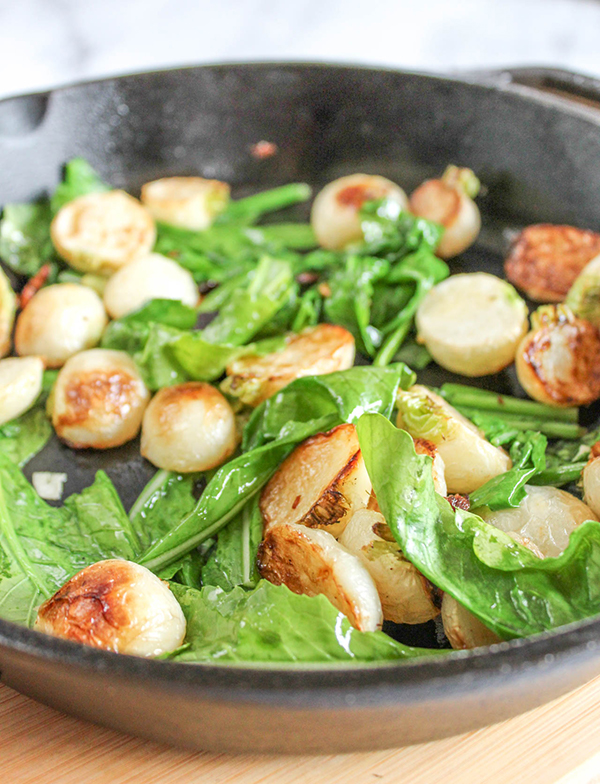 a close up of the greens and turnips in a cast iron pan