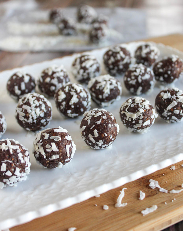 Chocolate almond bites covered in coconut on a white plate