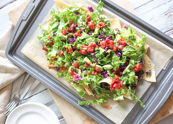 a picture of sheet pan nachos cooked on a pan with lettuce on top