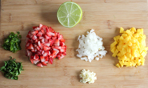 the ingredients: jalapeno peppers, chopped cilantro, strawberries, mango, lime, onion and garlic