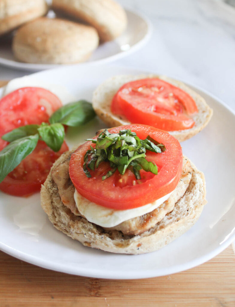 Open face chicken burger on a roll topped with tomatoes