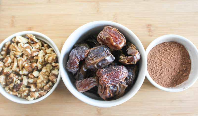 The ingredients in separate bowls: walnuts, dates, cocoa powder