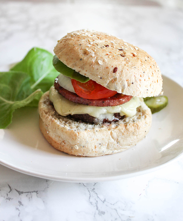 a hamburger with cheese lettuce tomatoes and pork roll on a roll