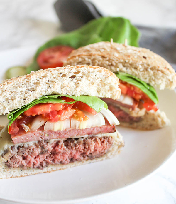 A close up of a burger cut in half on a roll